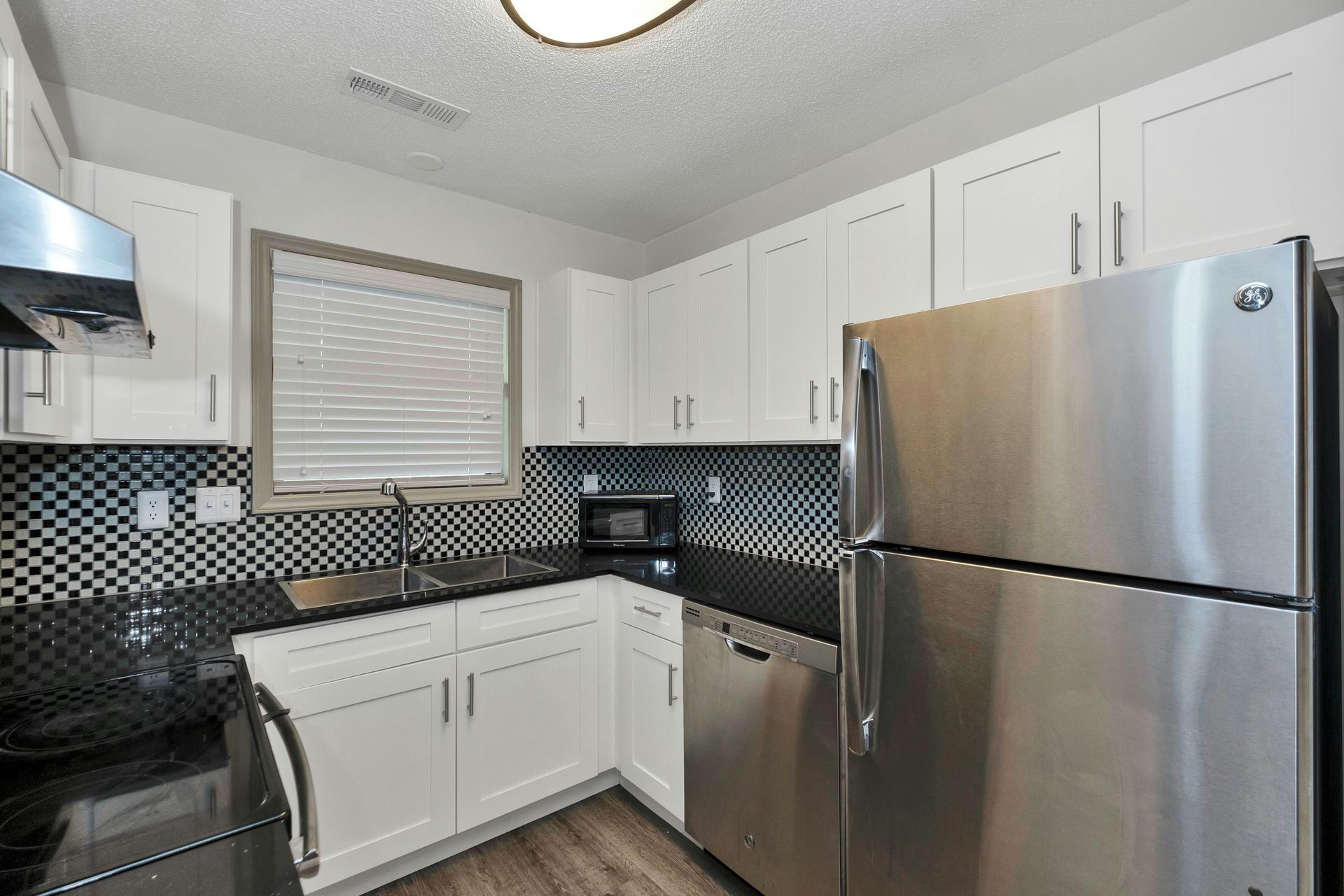 Modern kitchen with white cabinets, stainless steel appliances, and black tile backsplash