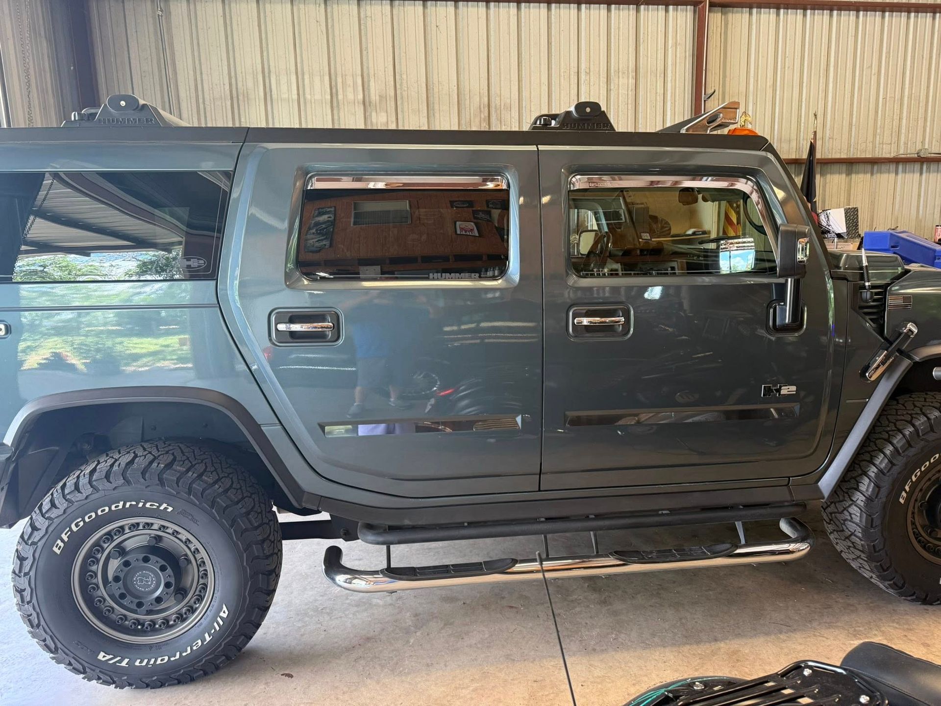 Dark gray Hummer SUV parked indoors, side view, with off-road tires and roof rack