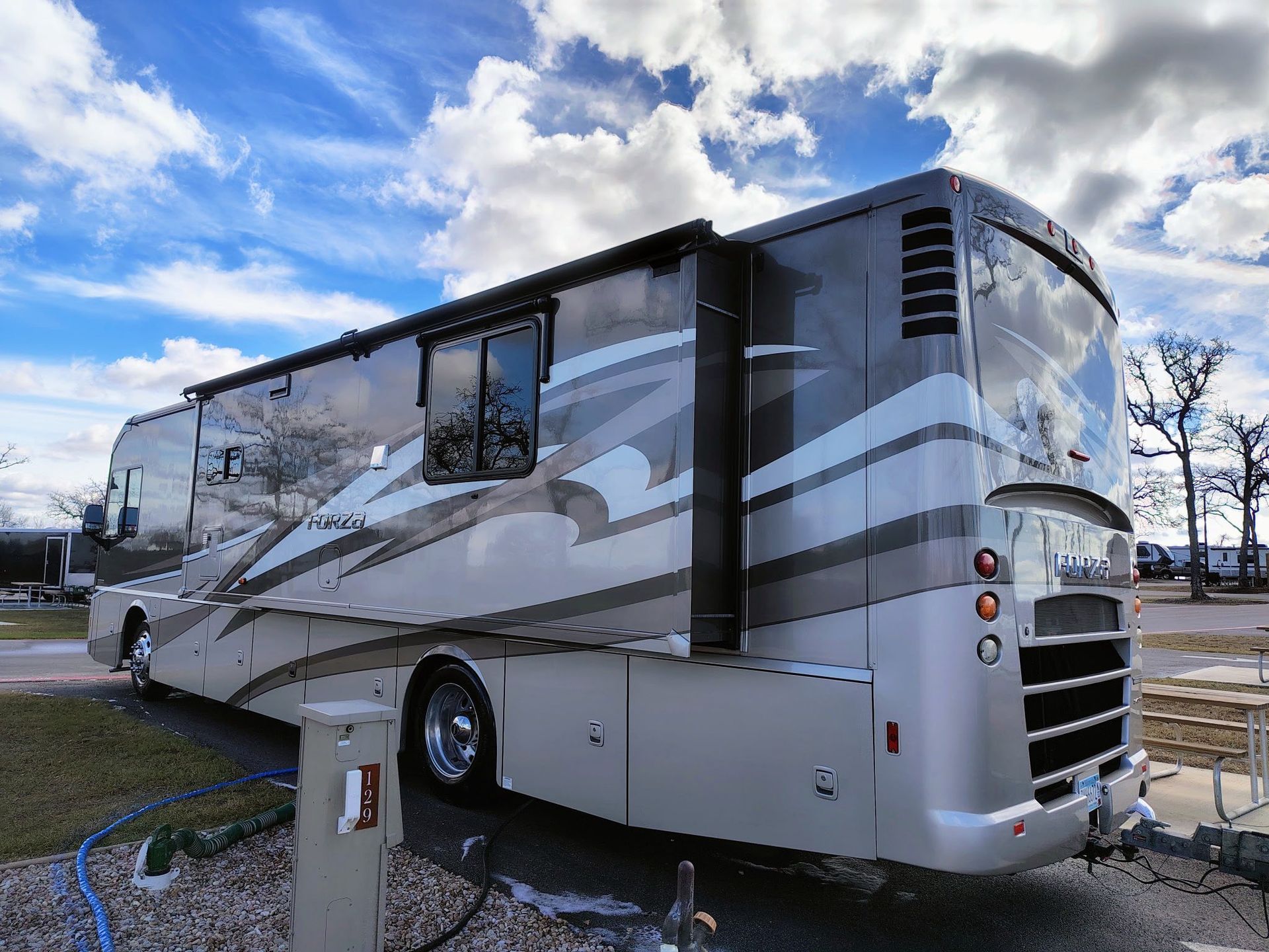 Large white and gray motorhome parked outdoors on a cloudy day