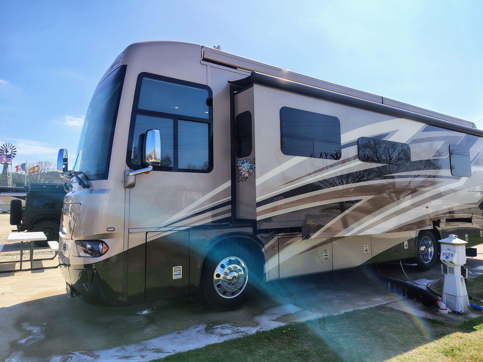 Large beige and brown motorhome parked outdoors in bright sunlight