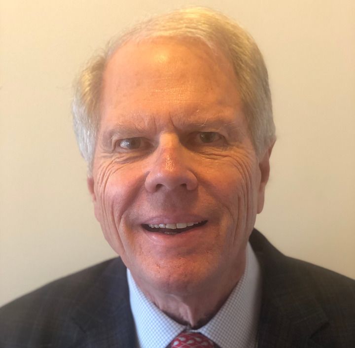 Smiling man in suit and tie, looking at the camera.