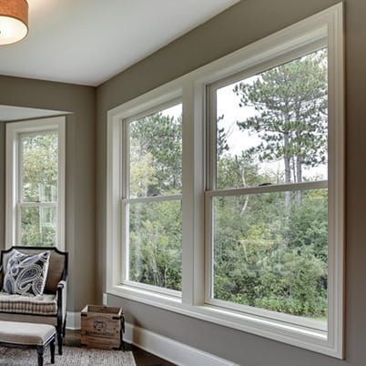 Bright living room with large windows overlooking trees and a cushioned bench in the corner