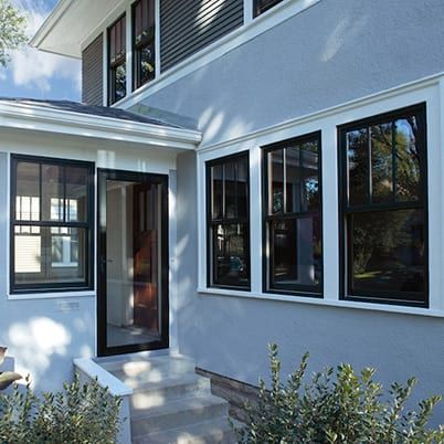Modern white house exterior with black-trim windows, front steps, and a small landscaped entryway
