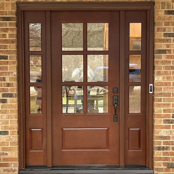 Brown double front door with glass panes set in a brick exterior wall