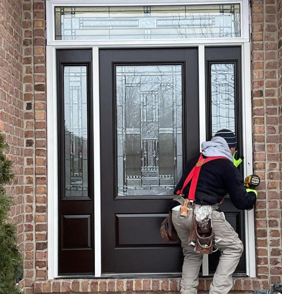 Person opening a front door with a key, standing on a brick porch.