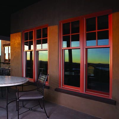 Patio with red-framed windows reflecting sunset light beside a round table and chairs