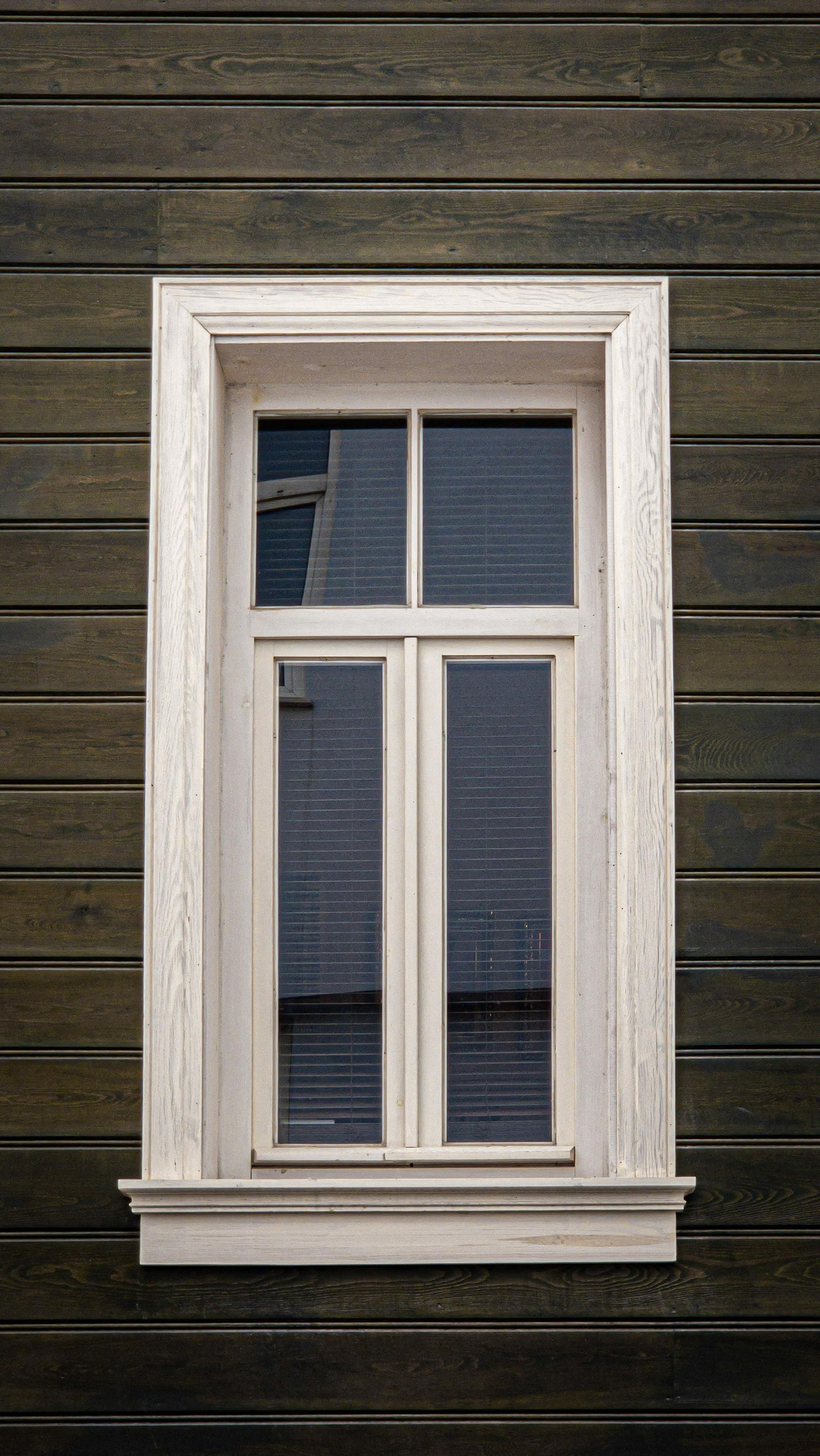 White-trimmed four-pane window on dark horizontal wooden siding