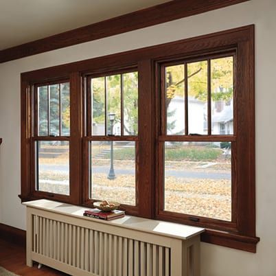 Wood-framed bay window above a radiator, with autumn trees visible outside.