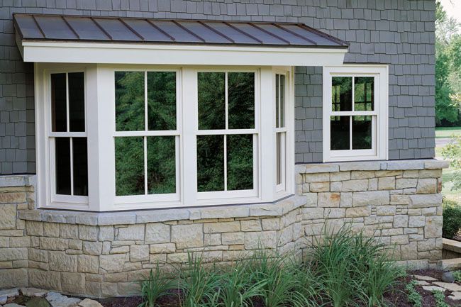 House exterior with a white bay window, gray shingle siding, and stone foundation