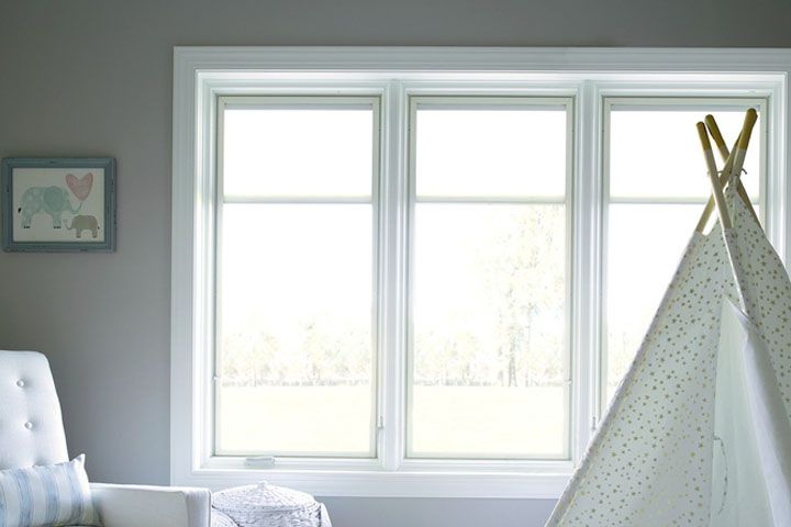 Bright nursery with a white teepee beside a large window and a tufted chair on the left