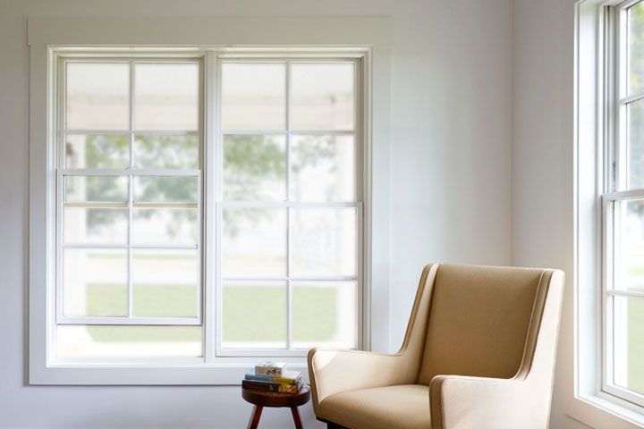 Bright living room with large windows, a beige armchair, and a small side table near the wall