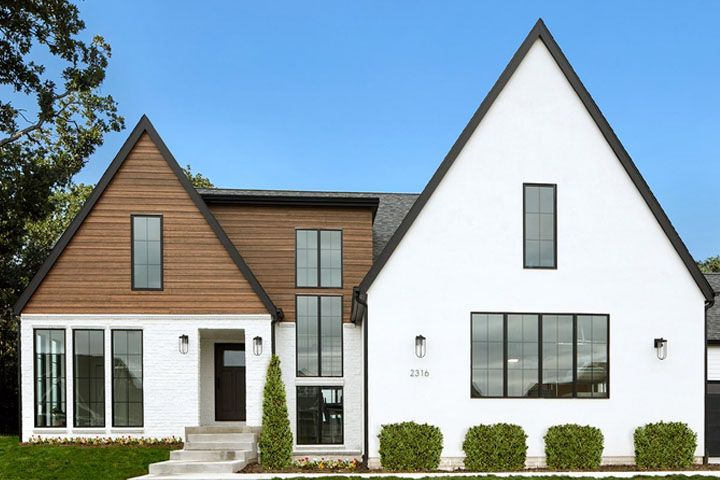Modern two-tone house with white and wood siding, large windows, and a front lawn