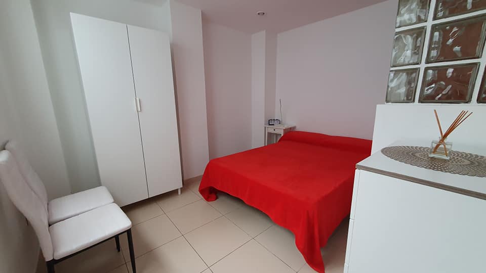 Ein Schlafzimmer mit Bett, Stühlen und Kleiderschrank.