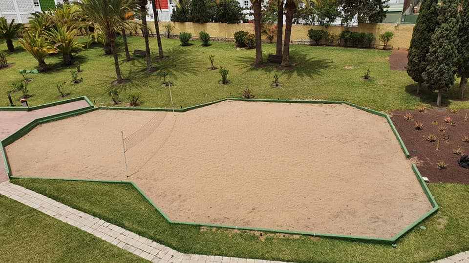Eine große Sandfläche in einem Park, umgeben von Gras und Bäumen