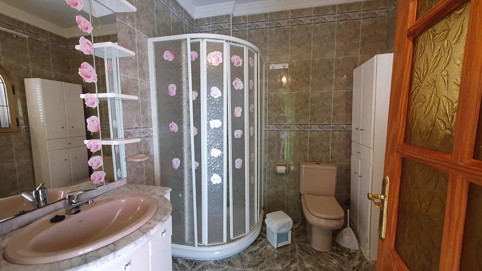 Ein Badezimmer mit Dusche, Toilette, Waschbecken und Spiegel.