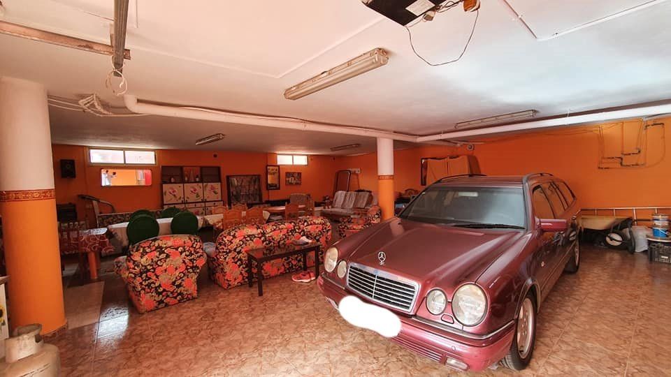 Ein rotes Auto steht in einer Garage neben einem Wohnzimmer