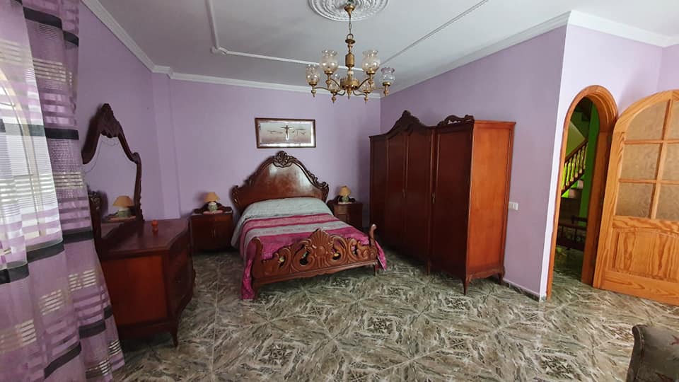 Ein Schlafzimmer mit Bett, Kommode, Spiegel und Kronleuchter.