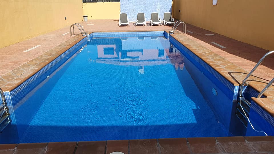 Ein großer blauer Swimmingpool mit Stühlen drumherum