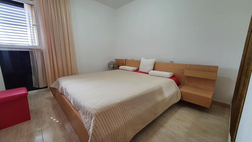 Ein Schlafzimmer mit einem großen Bett und einer roten Ottomane