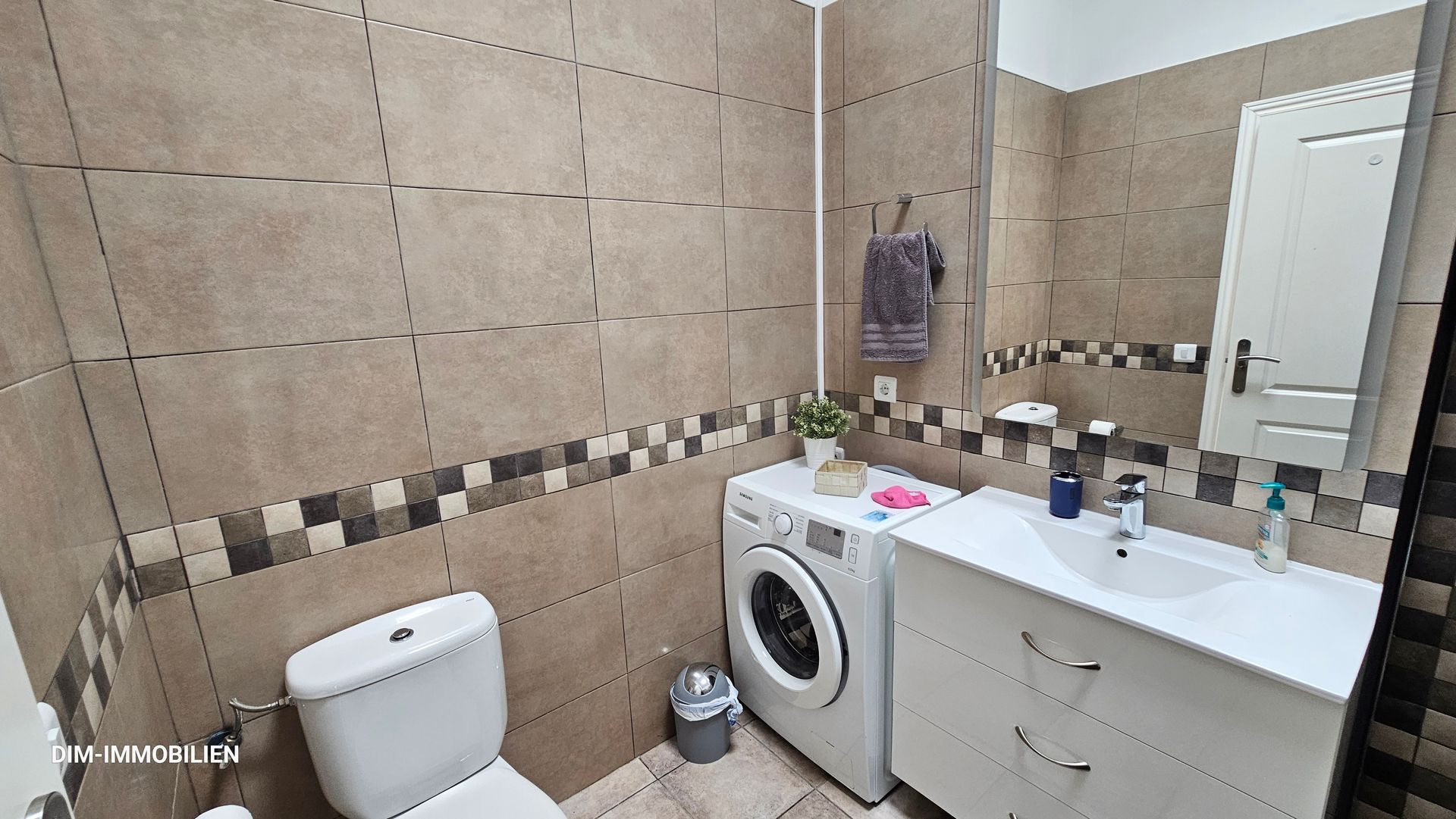 Ein Badezimmer mit Toilette, Waschbecken, Waschmaschine und Trockner.