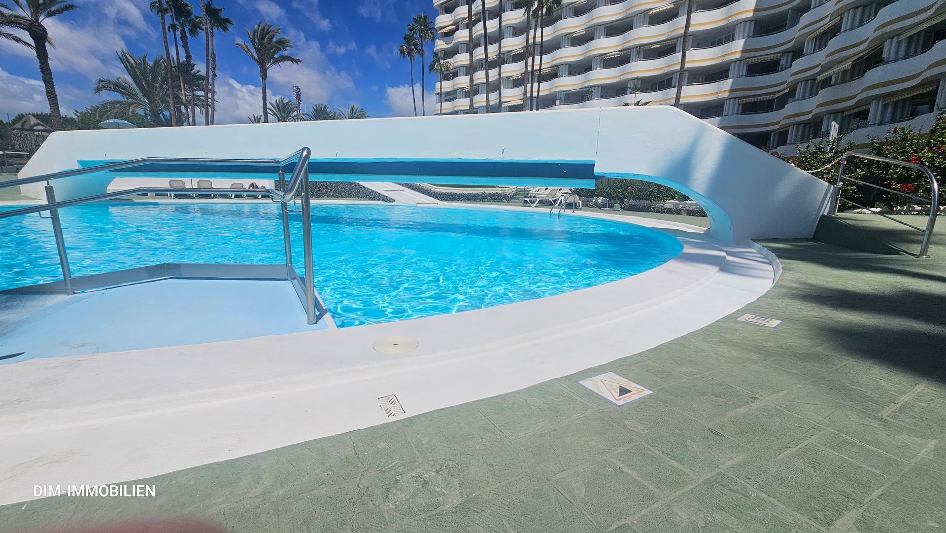 Ein großer Swimmingpool vor einem Gebäude mit Palmen
