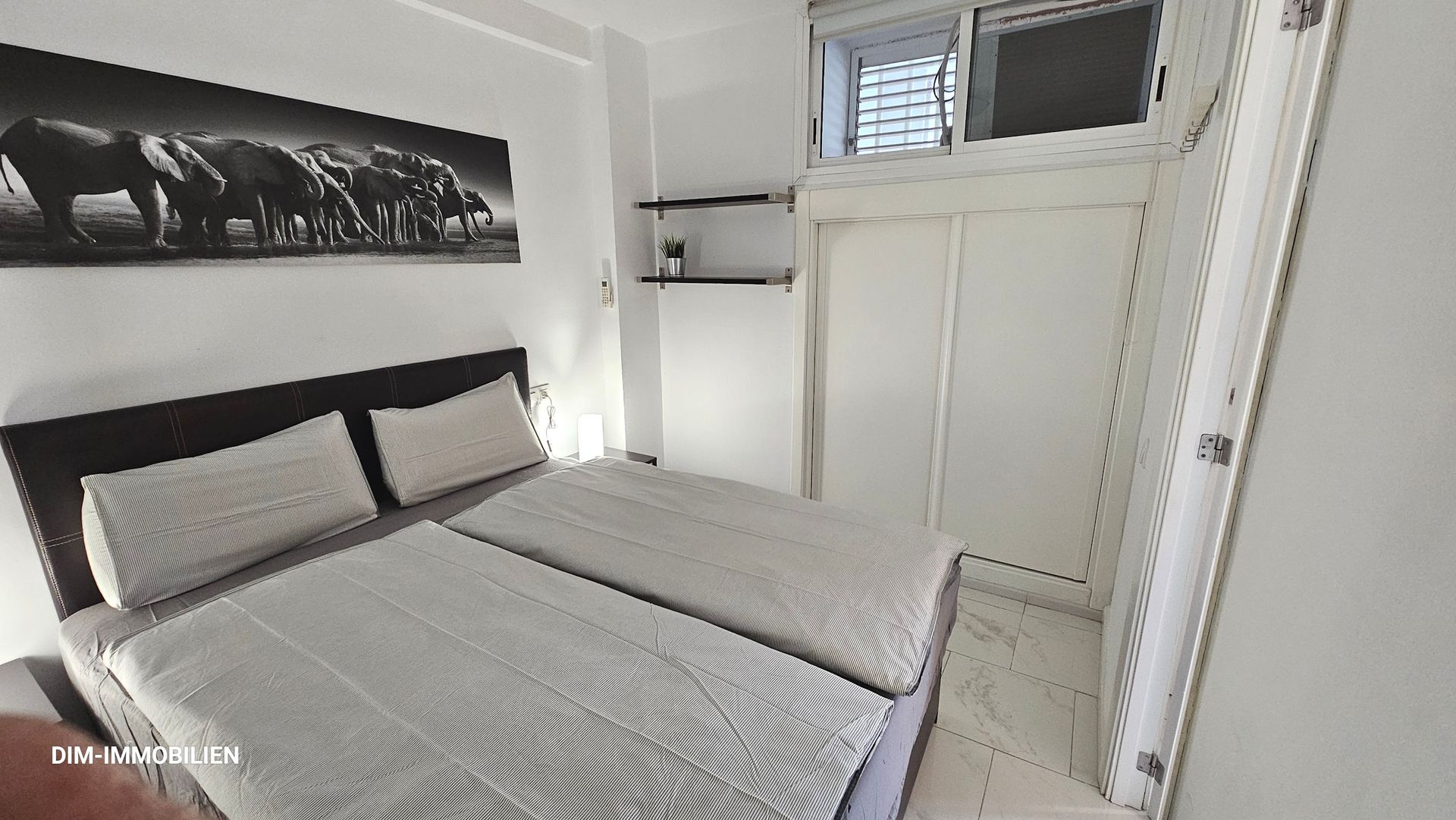 Ein Schlafzimmer mit zwei Betten und einem Gemälde an der Wand.