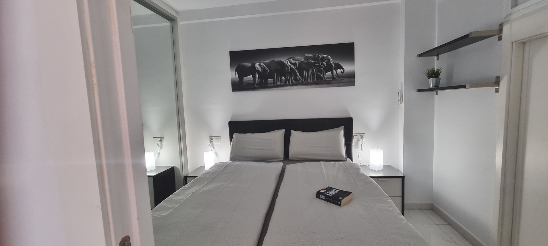 Ein Schlafzimmer mit einem Bett, Nachttischen, einem Spiegel und einem Gemälde an der Wand.