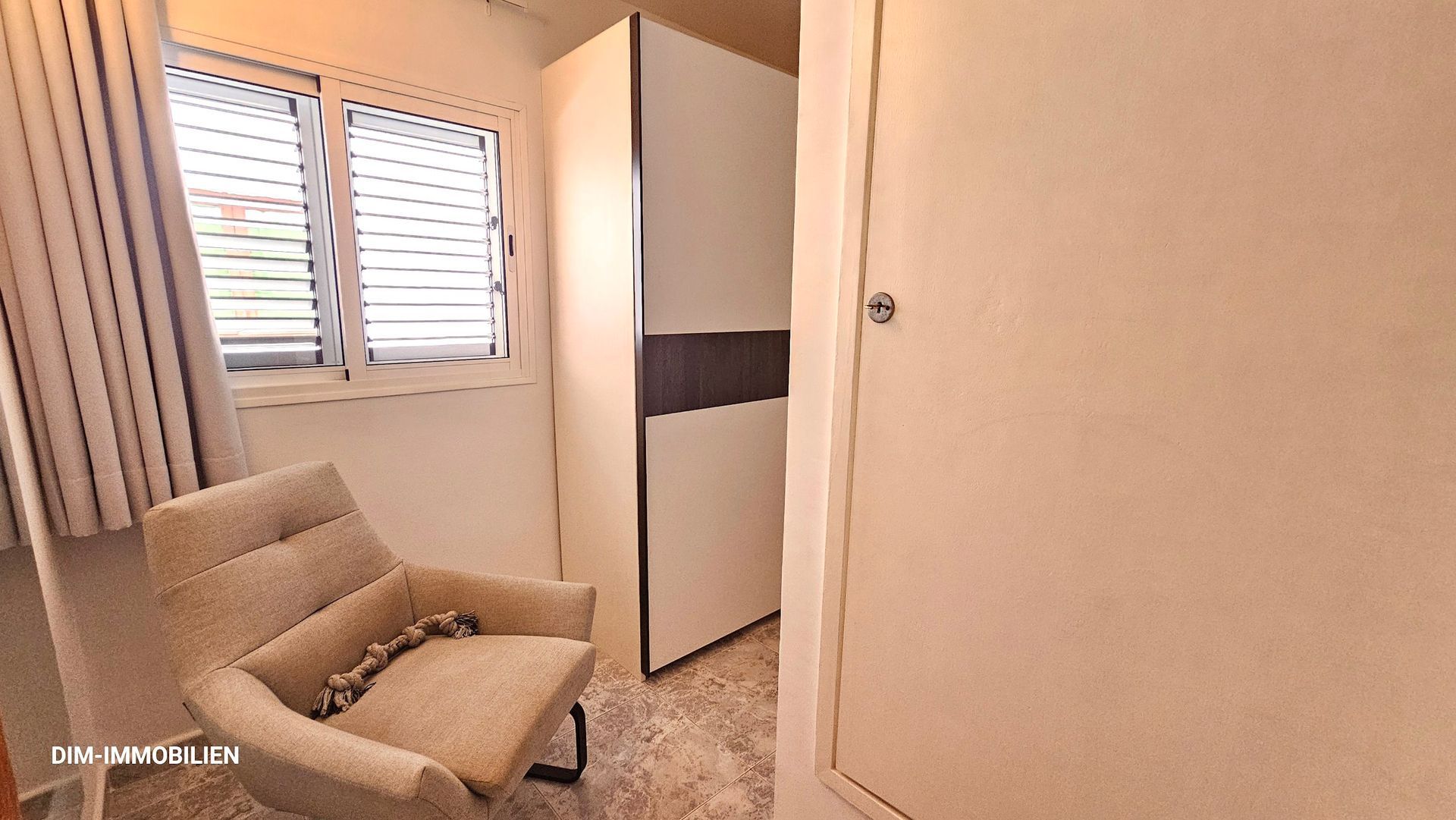 In einem Zimmer steht ein Stuhl neben einem Fenster.