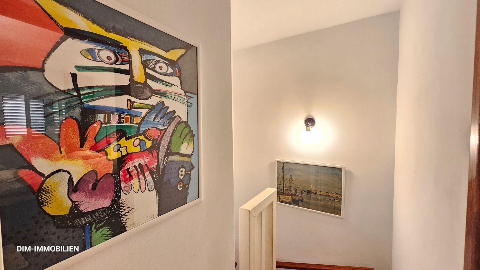 An einer Wand neben einer Treppe hängt ein farbenfrohes Gemälde.