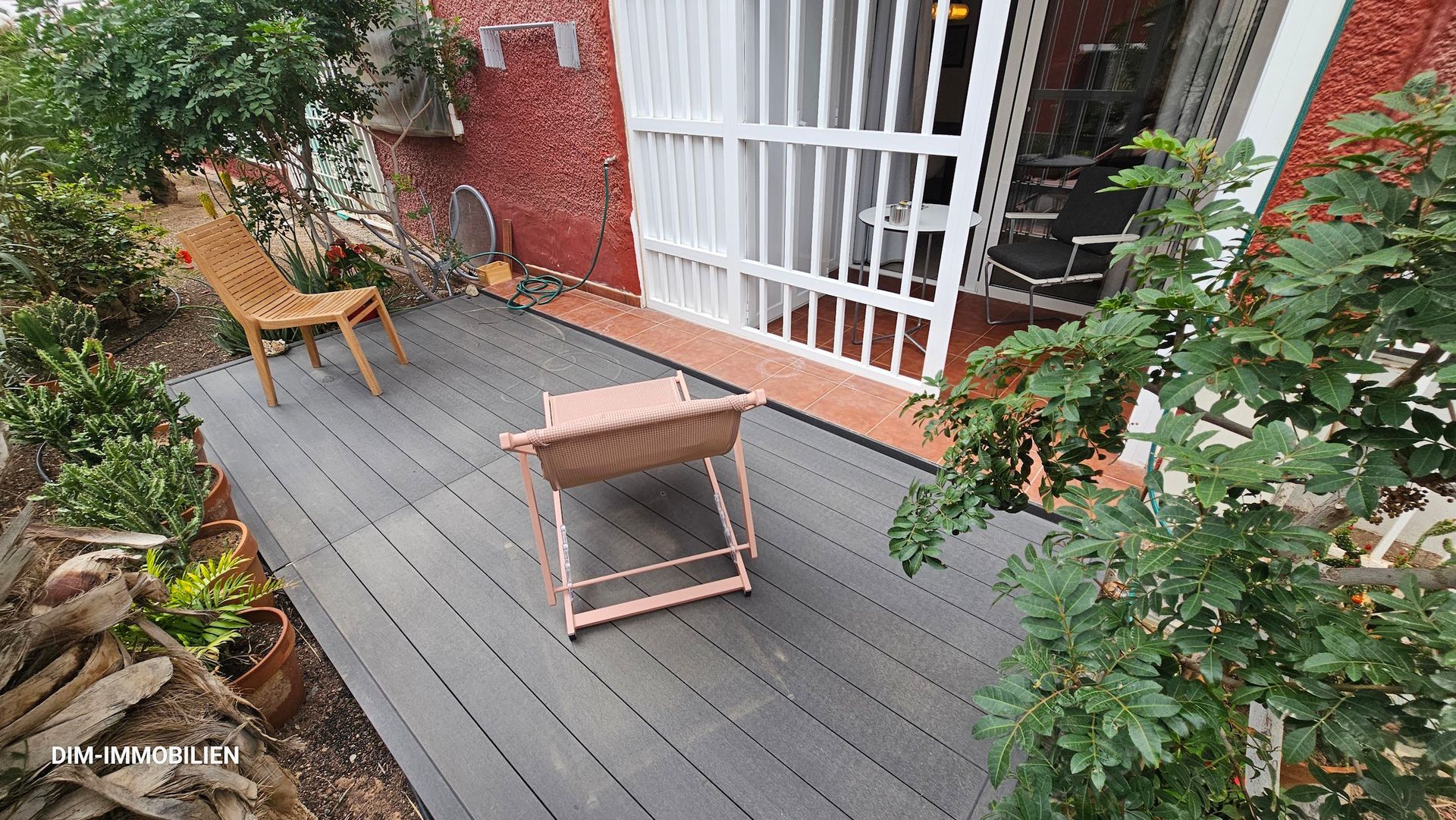 Eine Holzterrasse mit Stühlen und einem Tisch vor einem Haus.