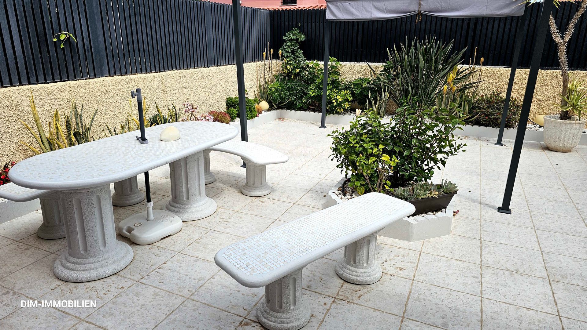 Eine Terrasse mit Tisch und Bänken und einem Baldachin