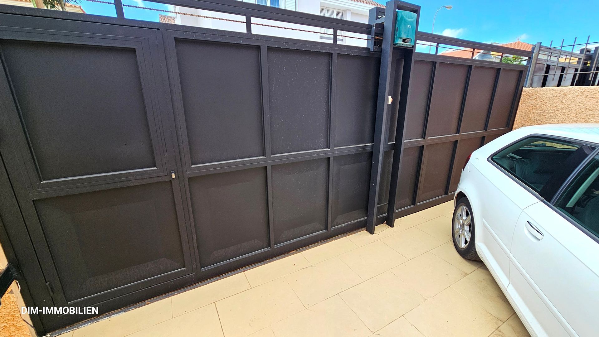 Ein weißes Auto parkt vor einem Schiebetor.