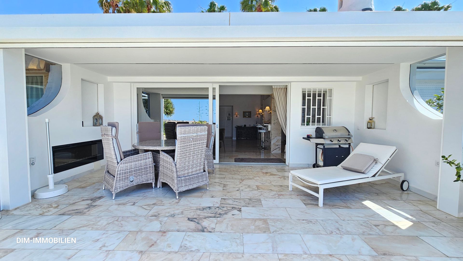 Eine Terrasse mit Tisch und Stühlen und einem Liegestuhl