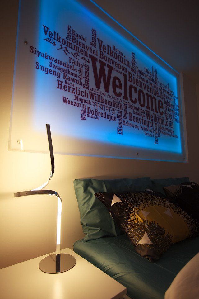 Ein Bett mit einer Lampe und einem Willkommensschild an der Wand darüber.