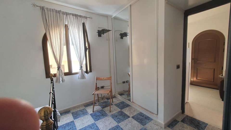 Ein Zimmer mit einem Stuhl und einem Spiegel an der Wand.