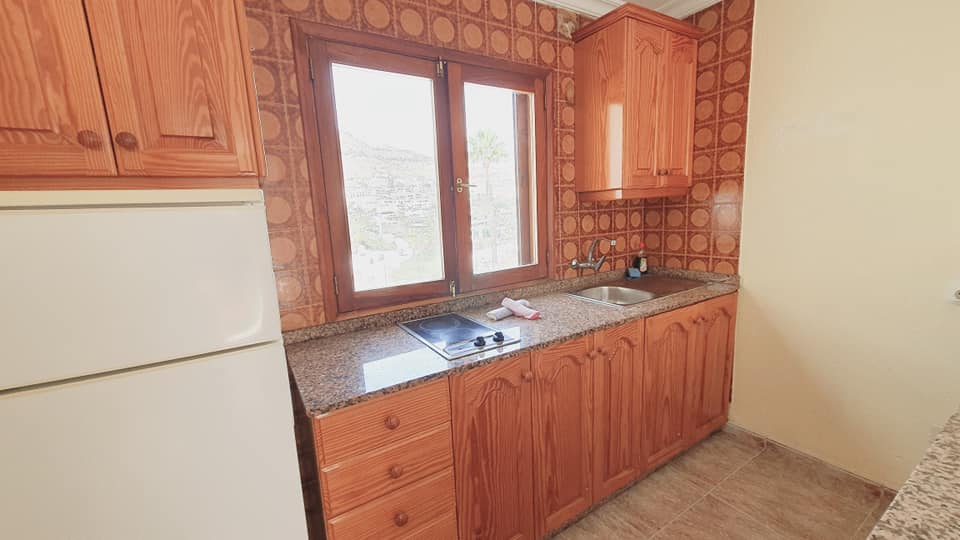Eine Küche mit Holzschränken und einem weißen Kühlschrank.