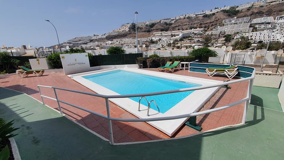 Ein großer Swimmingpool, umgeben von Stühlen und einem Zaun.