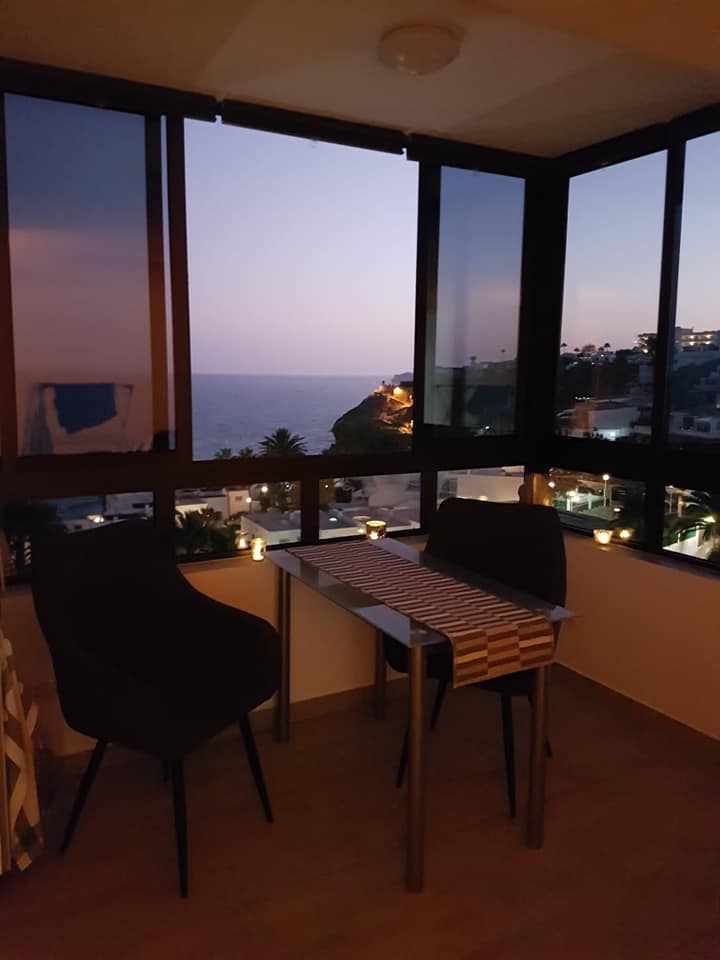 Ein Zimmer mit Tisch und Stühlen mit Blick auf das Meer