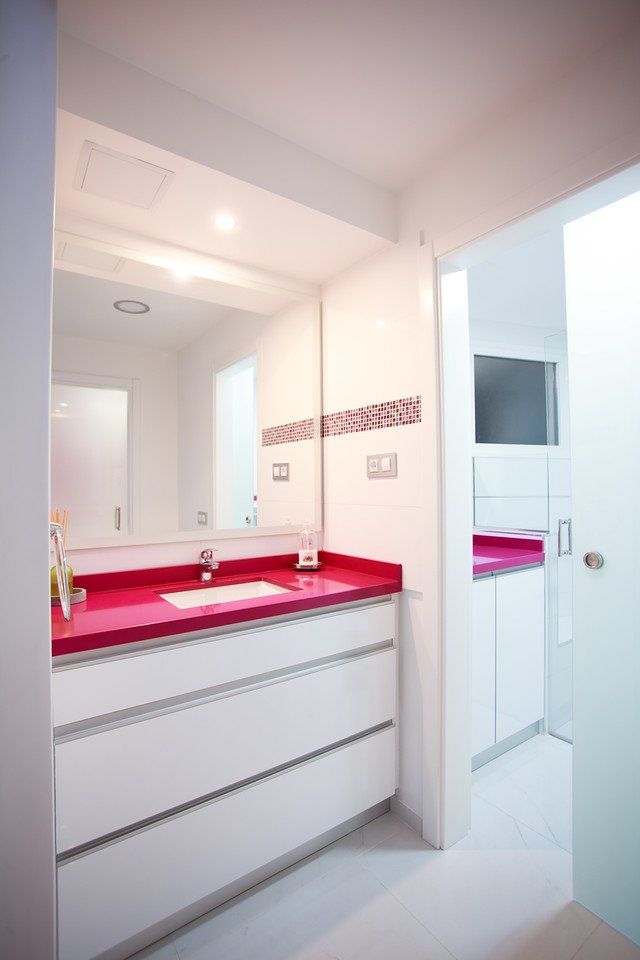 Ein Badezimmer mit weißen Schränken und einer rosa Waschtischplatte