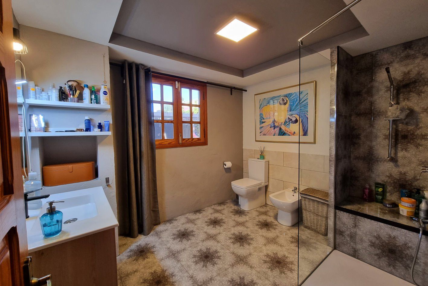 Ein Badezimmer mit Waschbecken, Toilette, Bidet und ebenerdiger Dusche.