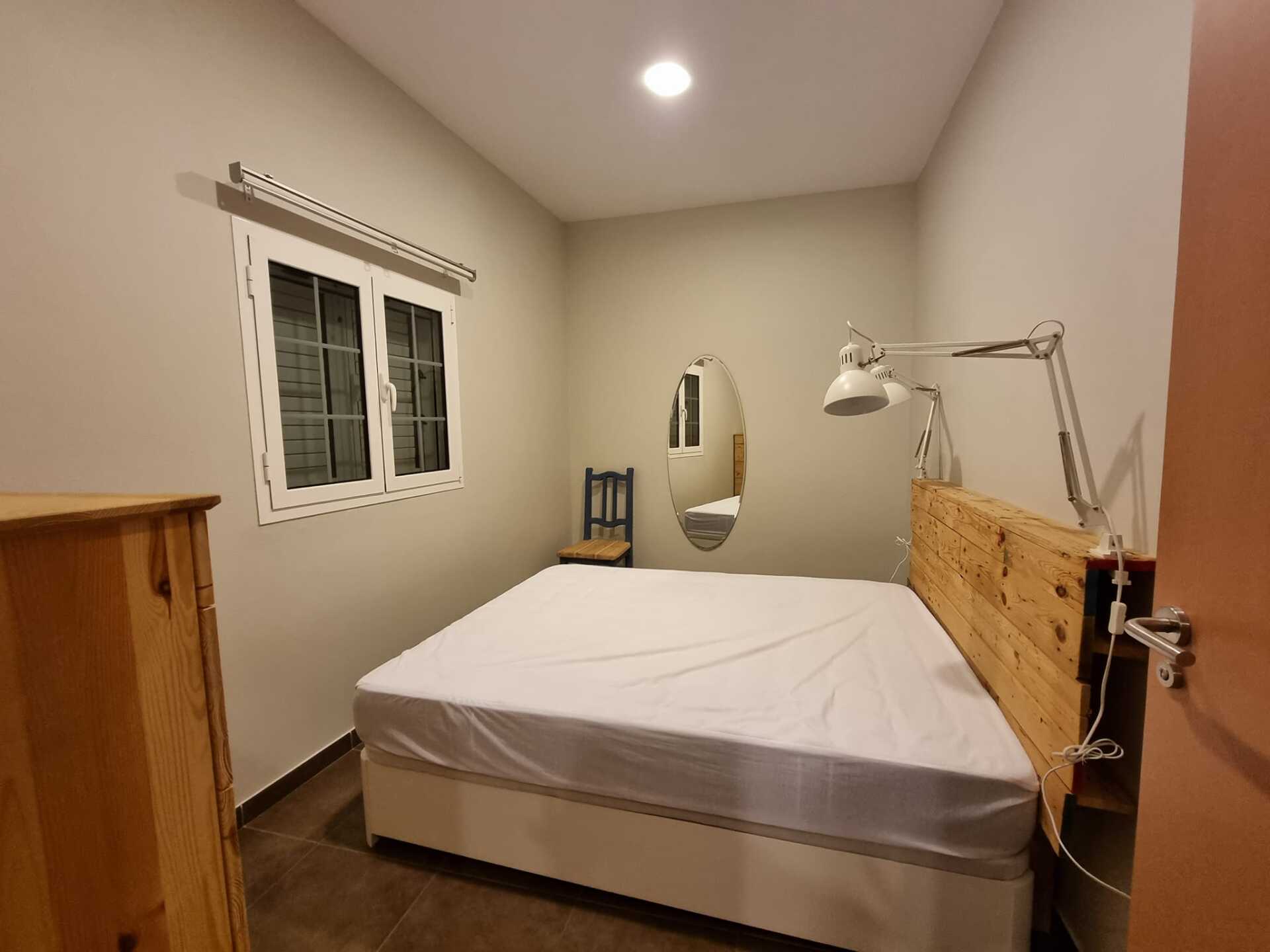 Ein Schlafzimmer mit Bett, Kommode, Stuhl und Spiegel.
