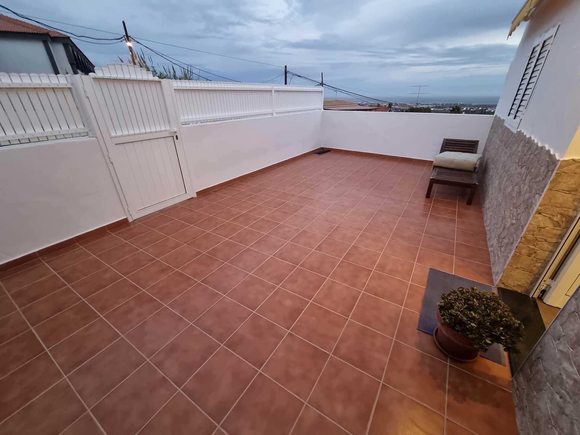 Eine Terrasse mit einem Stuhl und einer Topfpflanze darauf.