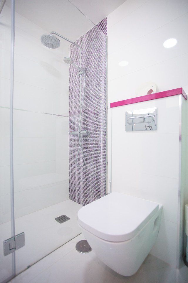 Ein Badezimmer mit Toilette, Dusche und violetten Fliesen.