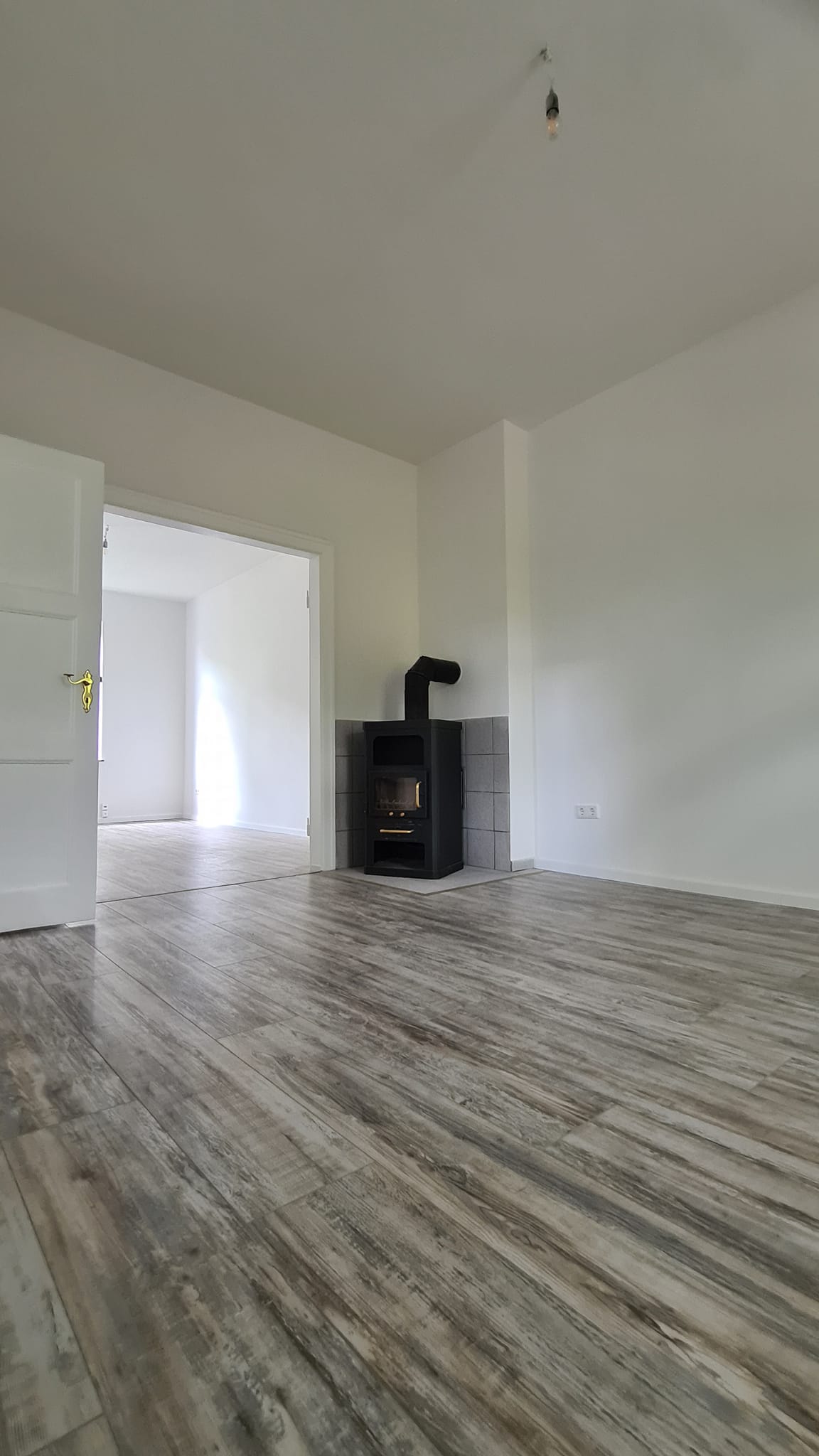 Ein leeres Wohnzimmer mit einem Holzofen in der Ecke.