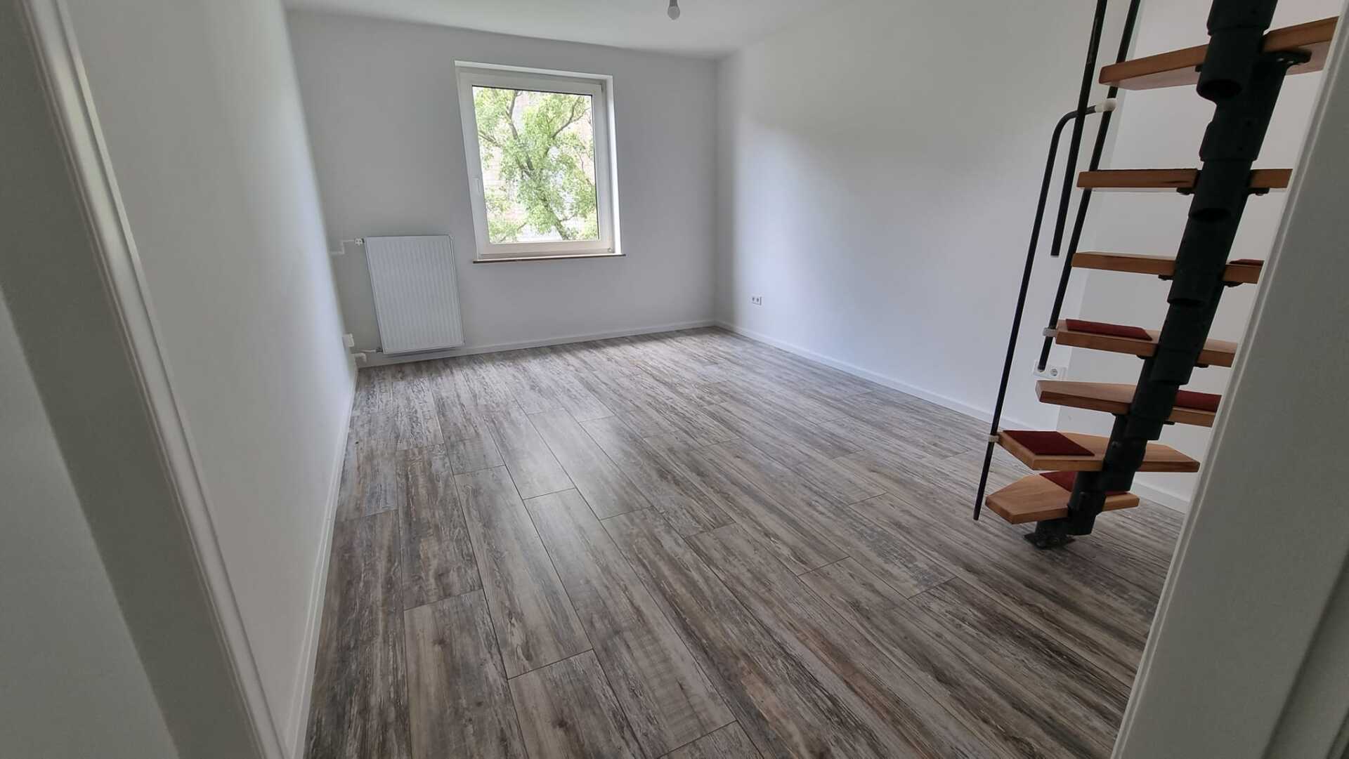Ein leerer Raum mit einer Wendeltreppe und einem Fenster.