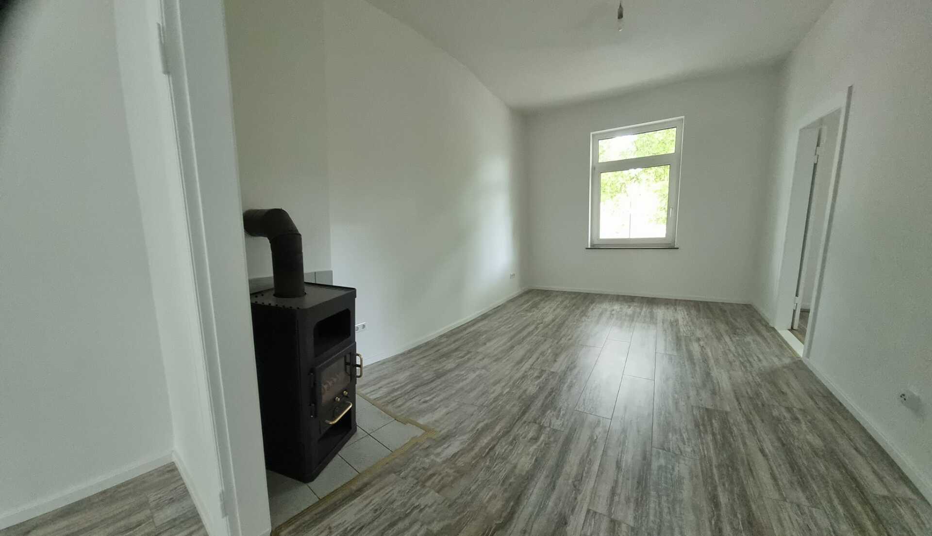 Ein Wohnzimmer mit Holzofen und Fenster.