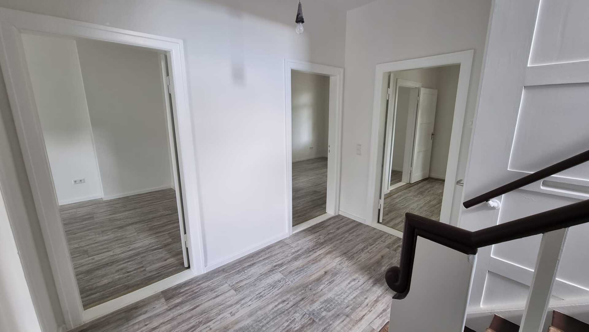 Ein Flur mit einer Treppe und zwei Spiegeln an der Wand.