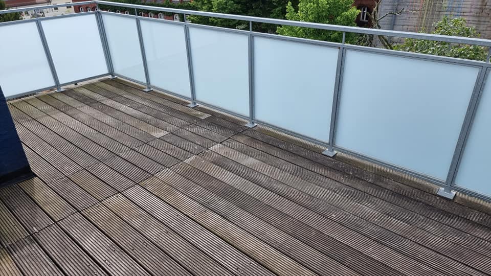 Ein Balkon mit Holzdeck und Glasgeländer.