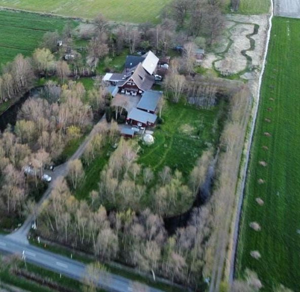 Eine Luftaufnahme eines Hauses, umgeben von Bäumen und Feldern