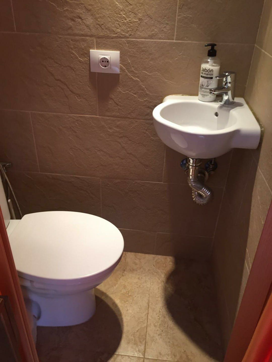 Ein Badezimmer mit Toilette, Waschbecken und Seifenspender